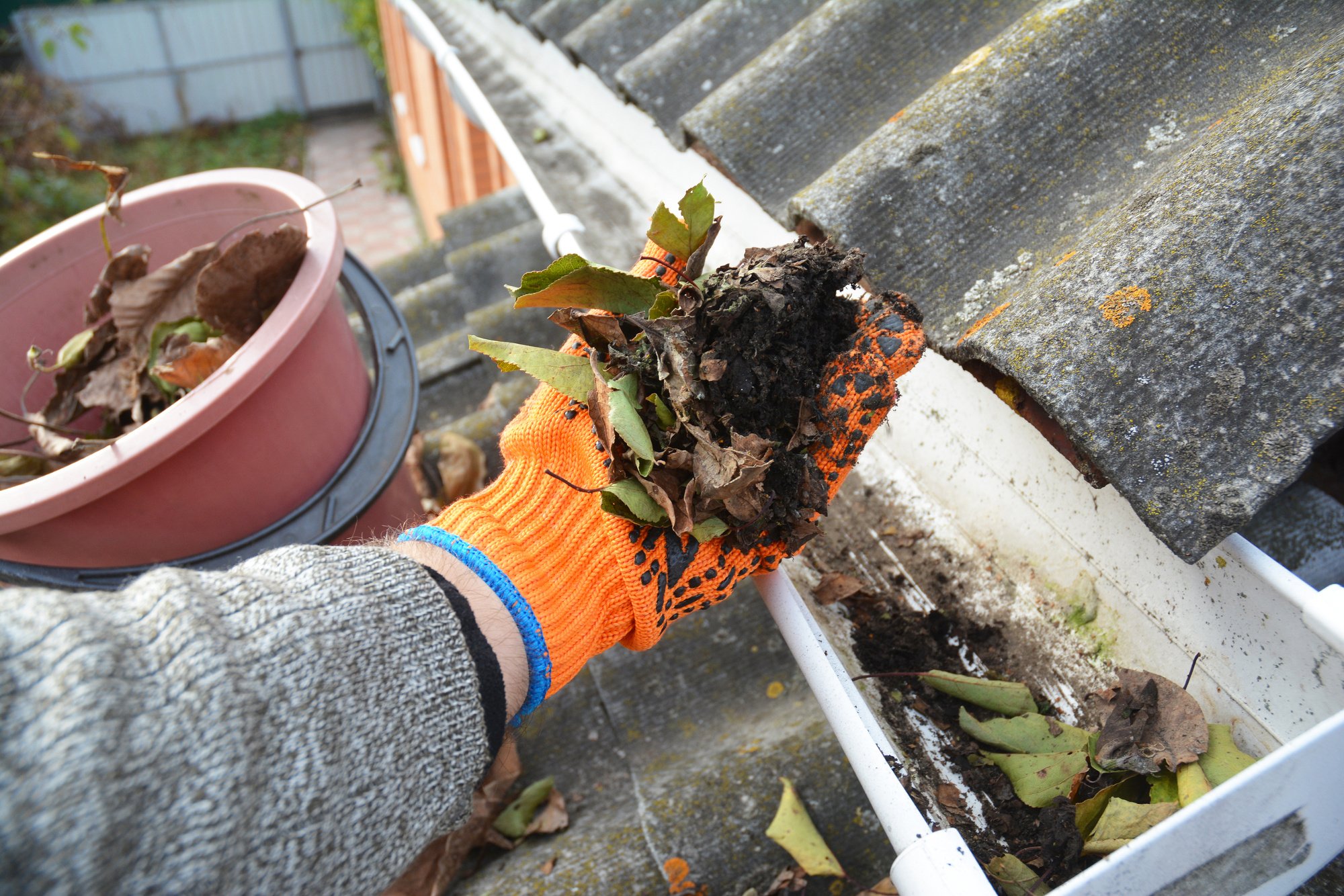 Rain Gutter Cleaning from Leaves in Autumn with hand. Roof Gutter Cleaning Tips. Clean Your Gutters Before They Clean Out Your Wallet. Gutter Cleaning.